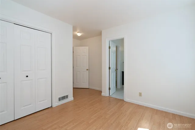 a view of an empty room with closet and wooden floor