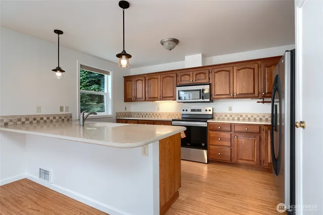 a kitchen with stainless steel appliances granite countertop a sink a stove and a refrigerator