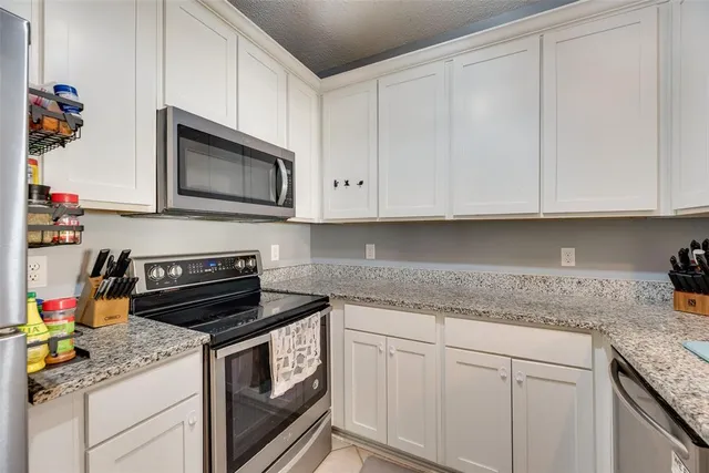 a kitchen with granite countertop white cabinets and stainless steel appliances