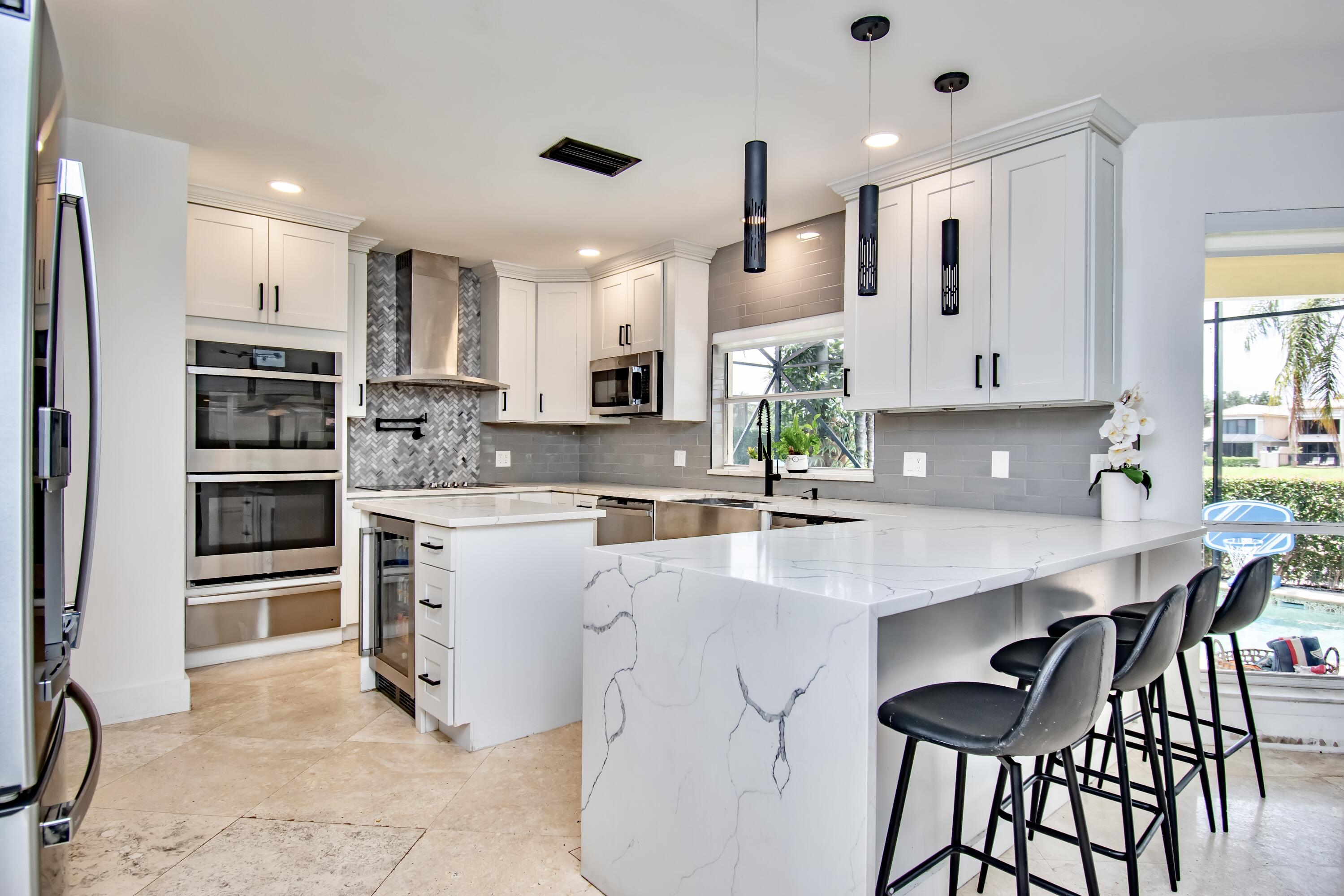 22568 Esplanada Circle Boca Raton, FL 33433 - Photo 15 of 50 a kitchen with stainless steel appliances kitchen island granite countertop a sink and cabinets