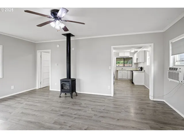 a view of a livingroom with furniture wooden floor a ceiling fan and windows