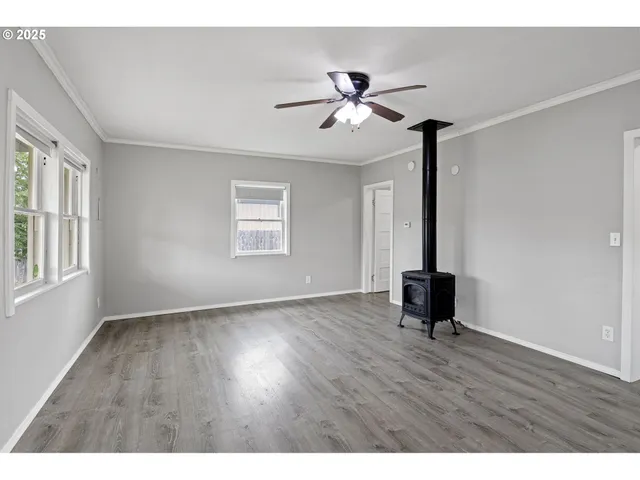 a view of an empty room with a window and wooden floor