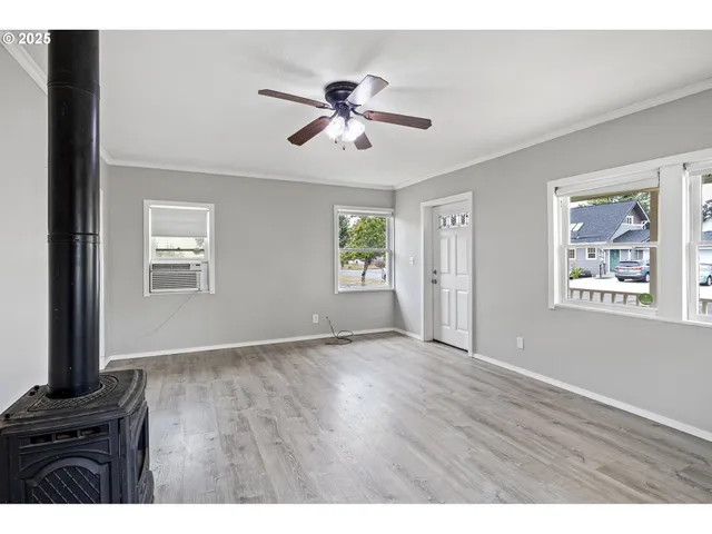 a view of an empty room with a window and wooden floor
