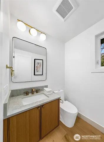 a bathroom with a granite countertop sink mirror vanity and toilet