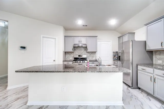 a large kitchen with kitchen island a stove a sink and a refrigerator