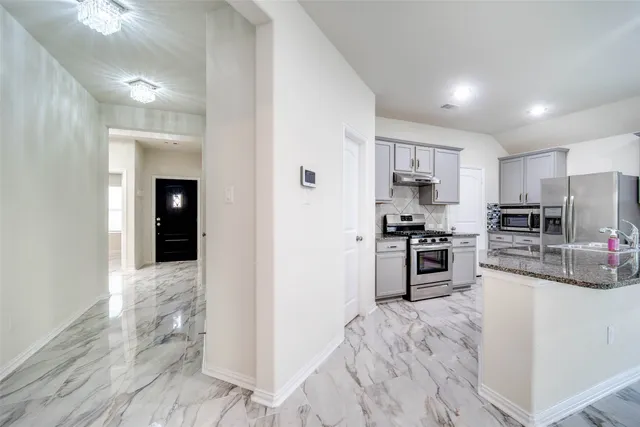a kitchen with granite countertop a refrigerator stove top oven and sink