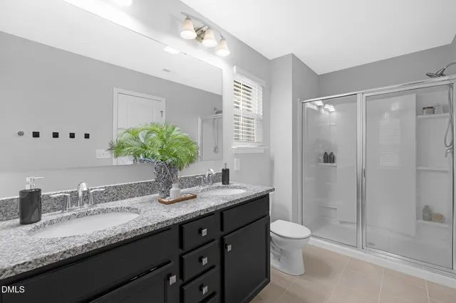 a bathroom with a granite countertop sink a toilet a large mirror and shower