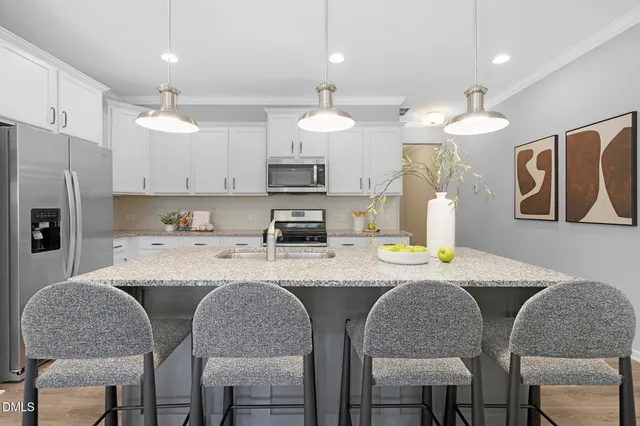 a kitchen with stainless steel appliances granite countertop a sink a stove a refrigerator with a dining table and chairs