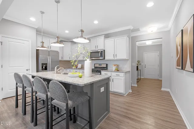 a kitchen with kitchen island granite countertop wooden floors and white cabinets