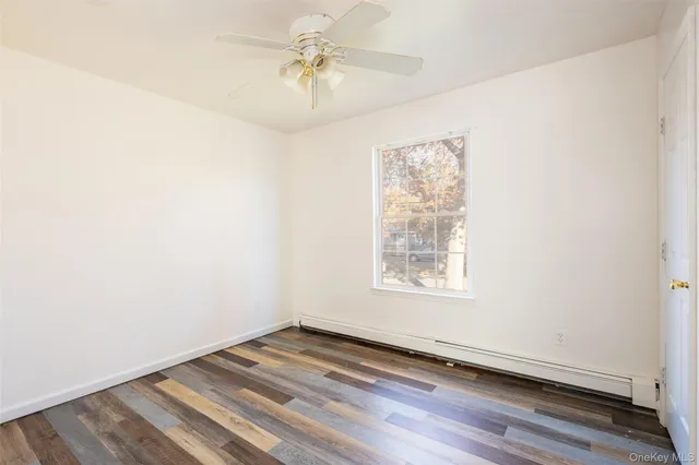 an empty room with wooden floor closet and windows