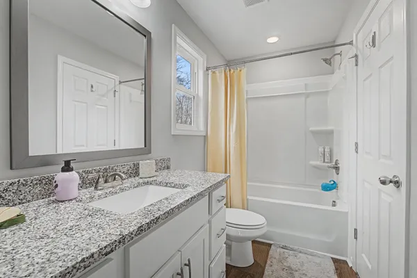 a kitchen with stainless steel appliances granite countertop a refrigerator a stove a sink dishwasher and white cabinets with wooden floor