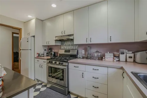 a kitchen with stainless steel appliances granite countertop a stove a refrigerator and a white cabinets