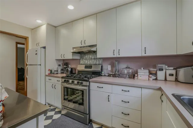 a kitchen with stainless steel appliances granite countertop a stove a refrigerator and a white cabinets
