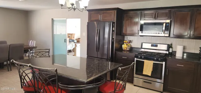 a kitchen with granite countertop stainless steel appliances a stove refrigerator and microwave