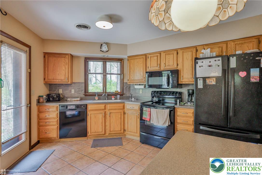 1208 Rone Drive Wind Gap, PA 18091 - Photo 25 of 78 a kitchen with stainless steel appliances granite countertop a stove top oven a sink dishwasher a dining table and chairs with wooden floor