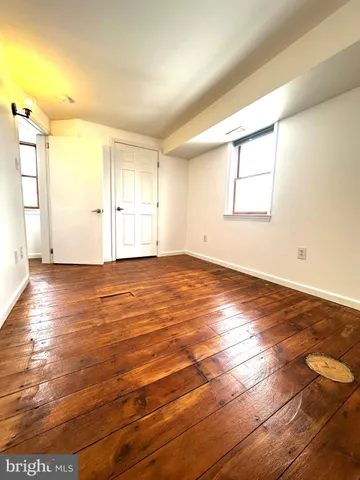 an empty room with wooden floor and windows with curtains