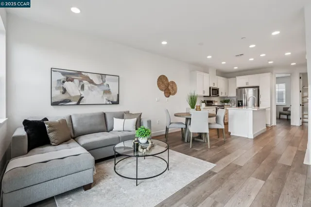 a living room with furniture kitchen view and a wooden floor