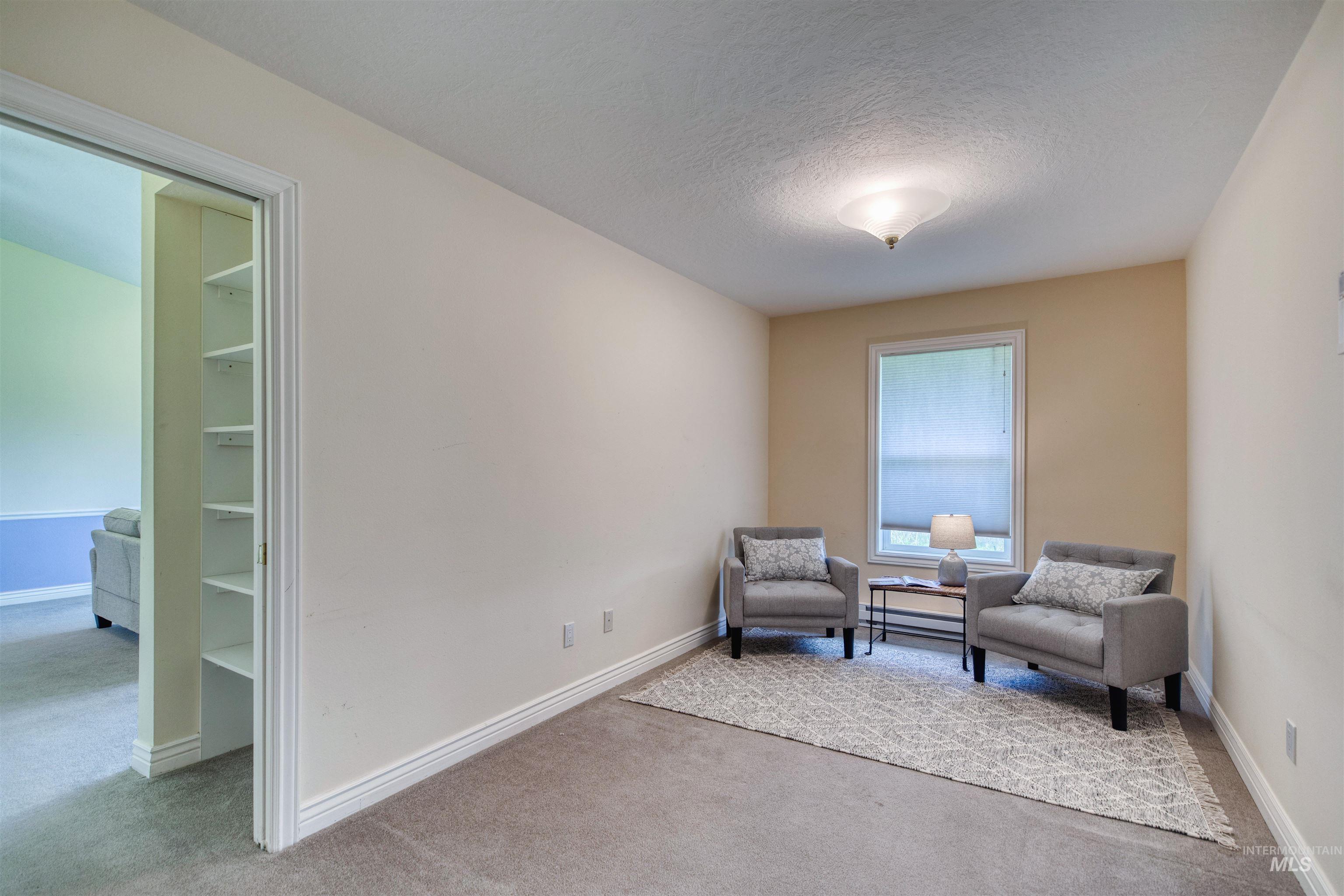 1295 15th Street Vale, OR 97918 - Photo 14 of 50 Living area featuring light colored carpet, a textured ceiling, and a baseboard radiator