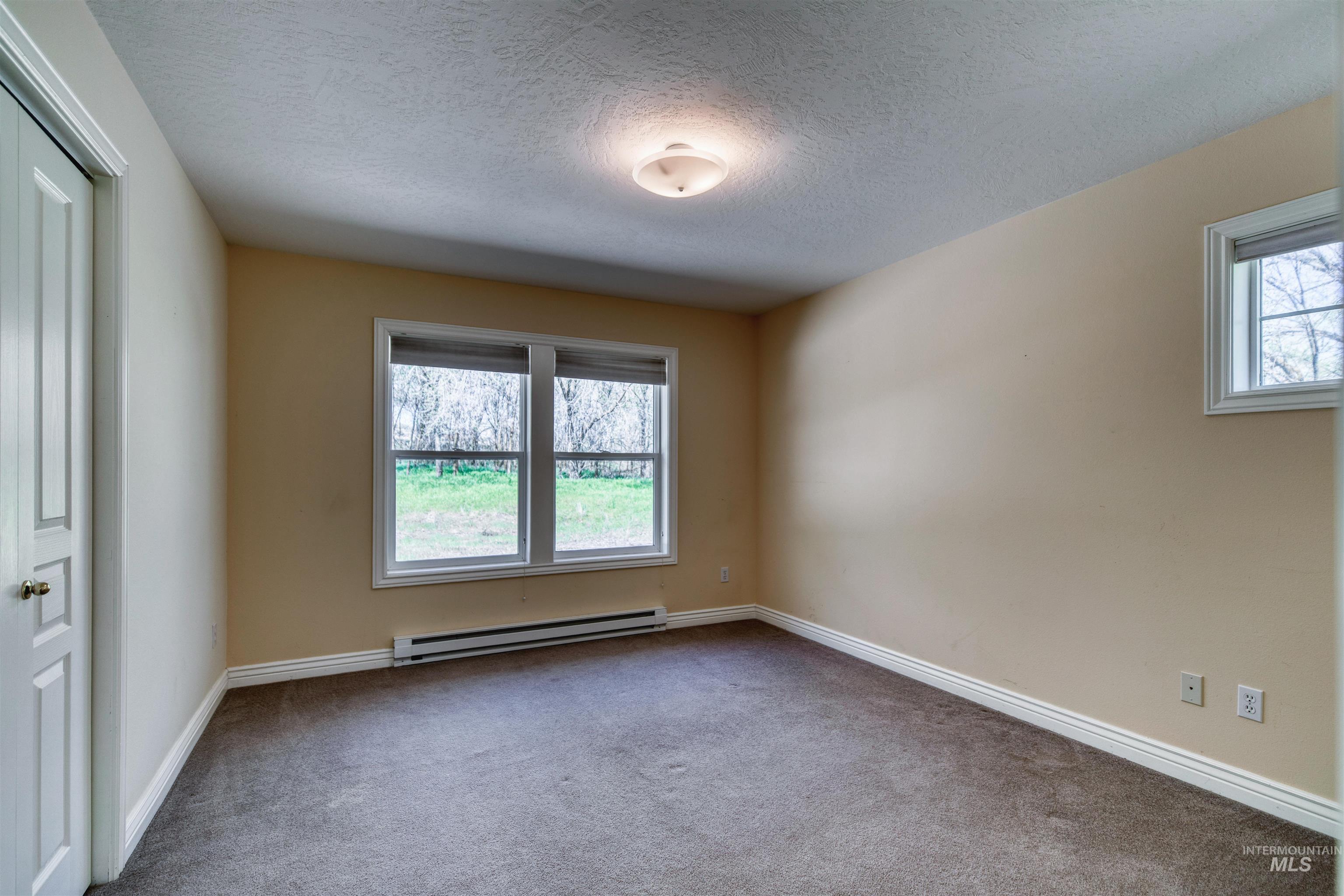 1295 15th Street Vale, OR 97918 - Photo 21 of 50 Carpeted empty room featuring a textured ceiling and a baseboard heating unit