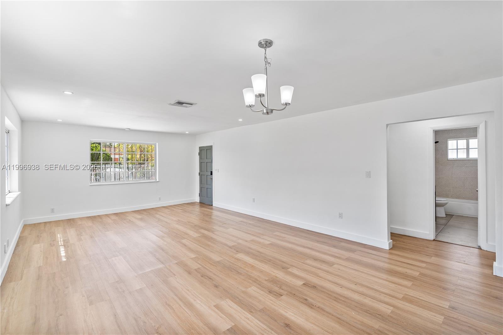 361 East 39th Street, Unit 1 Hialeah, FL 33013 - Photo 7 of 47 an empty room with wooden floor chandelier and windows