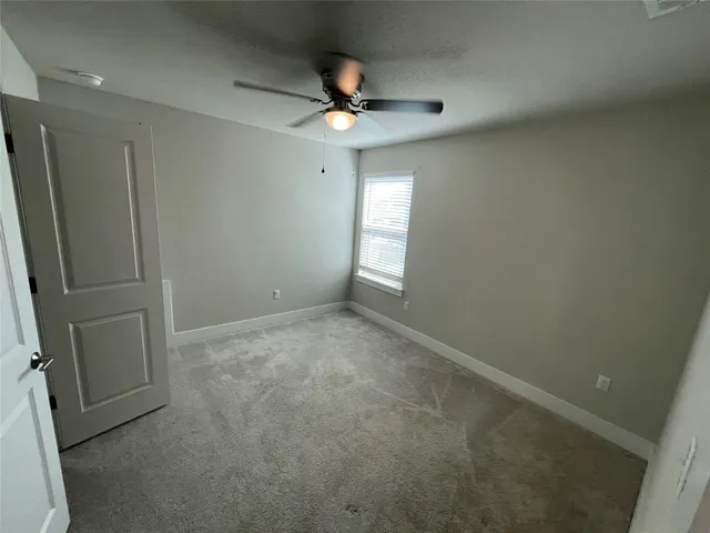 an empty room with a ceiling fan and window