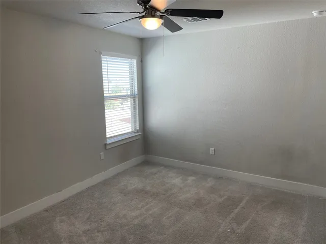an empty room with a window and a fan
