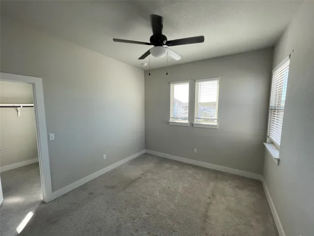 an empty room with windows and fan