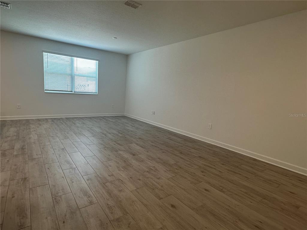 3128 Addison Boulevard St. Cloud, FL 34771 - Photo 16 of 35 a view of an empty room with wooden floor and a window