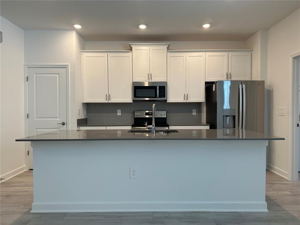 3128 Addison Boulevard St. Cloud, FL 34771 - Photo 4 of 35 a kitchen with stainless steel appliances granite countertop a refrigerator a stove a sink and a microwave
