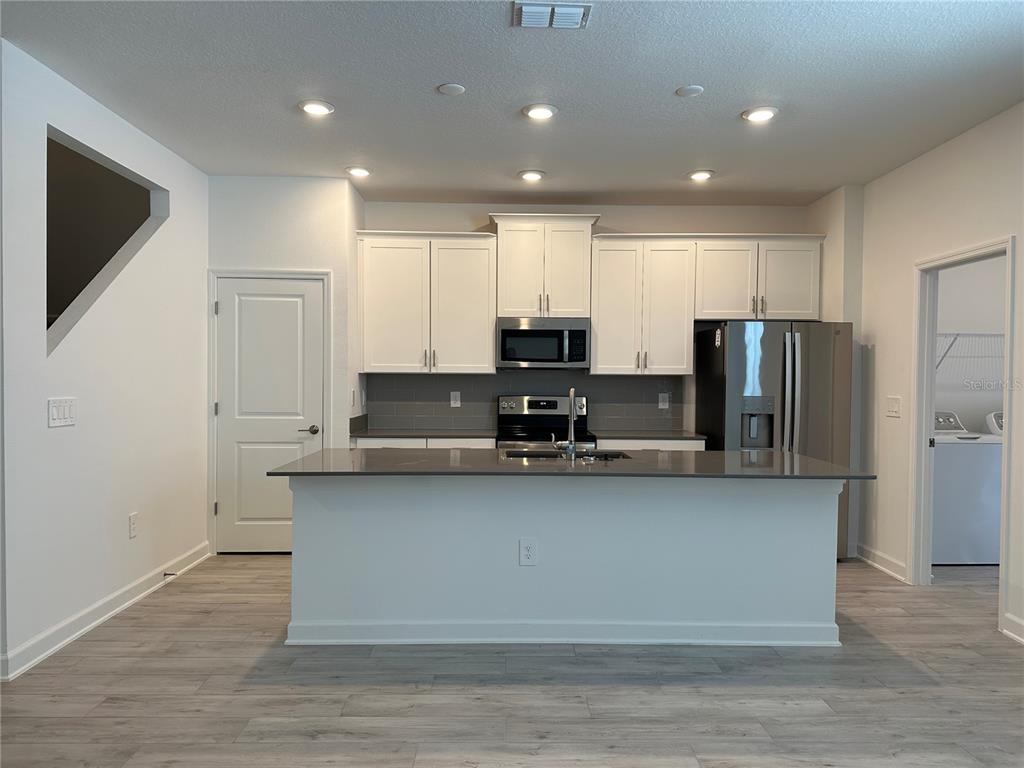 3128 Addison Boulevard St. Cloud, FL 34771 - Photo 5 of 35 a large kitchen with stainless steel appliances granite countertop a stove a refrigerator a sink and a microwave