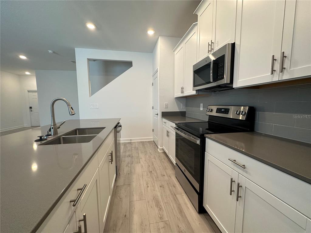 3128 Addison Boulevard St. Cloud, FL 34771 - Photo 7 of 35 a kitchen with stainless steel appliances granite countertop a sink a stove top oven and wooden floors