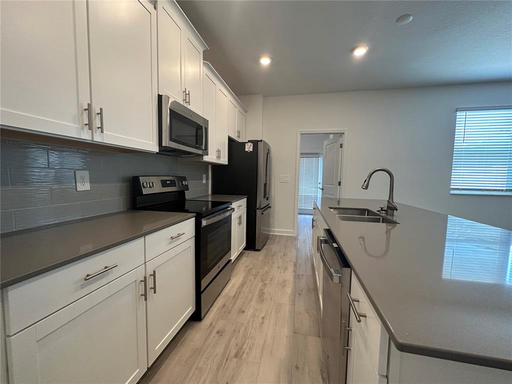 3128 Addison Boulevard St. Cloud, FL 34771 - Photo 8 of 35 a kitchen with stainless steel appliances a sink a stove top oven a refrigerator cabinets and a center island