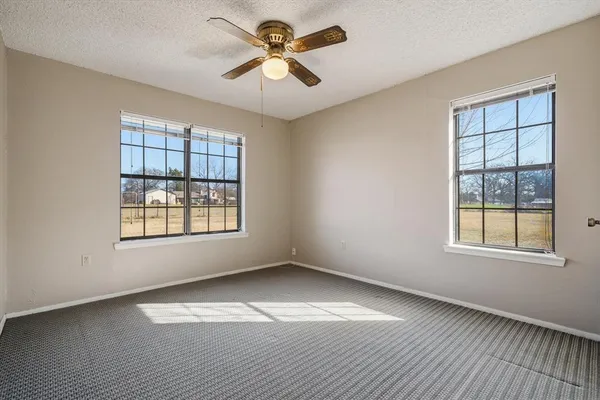 an empty room with windows and fan
