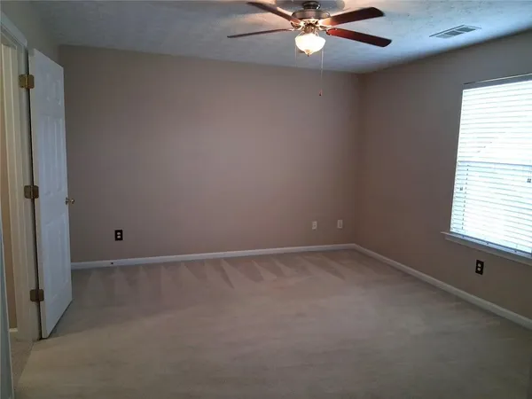an empty room with a window and a fan