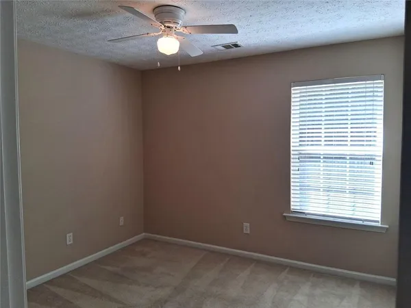 an empty room with a window and a fan