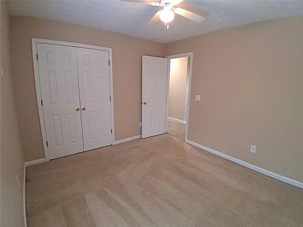 en empty room with windows and chandelier fan