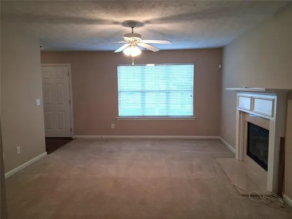 an empty room with chandelier fan and windows