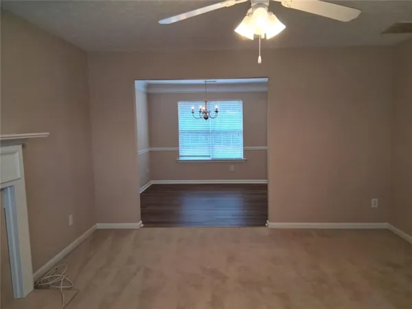 an empty room with a window and a chandelier fan
