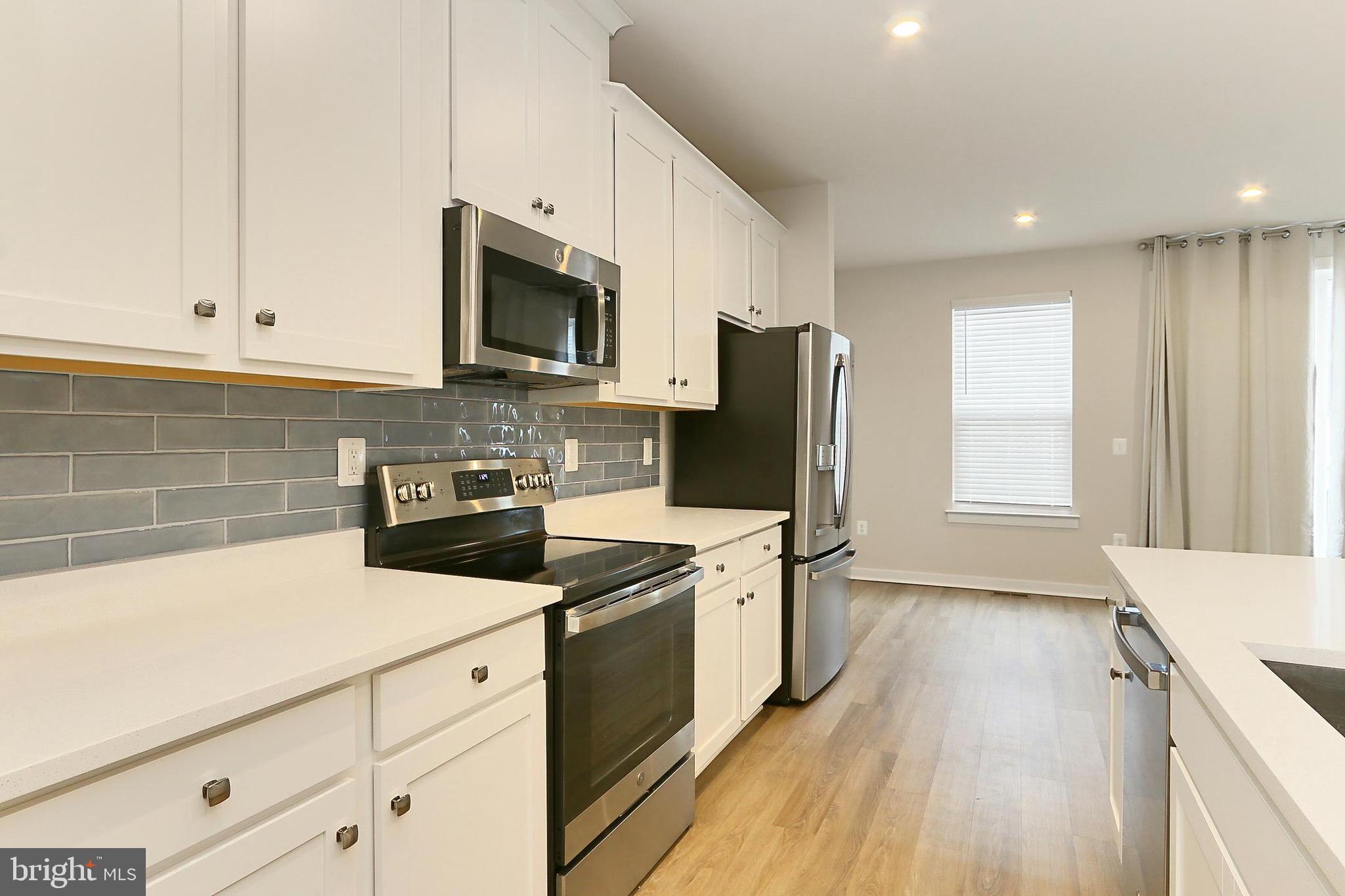 14176 Gypsum Loop Chantilly, VA 20151 - Photo 20 of 43 a kitchen with stainless steel appliances a stove top oven a sink a refrigerator white cabinets and wooden floor