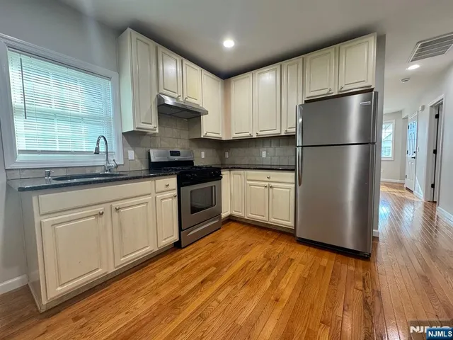 a kitchen with granite countertop stainless steel appliances a refrigerator sink and cabinets