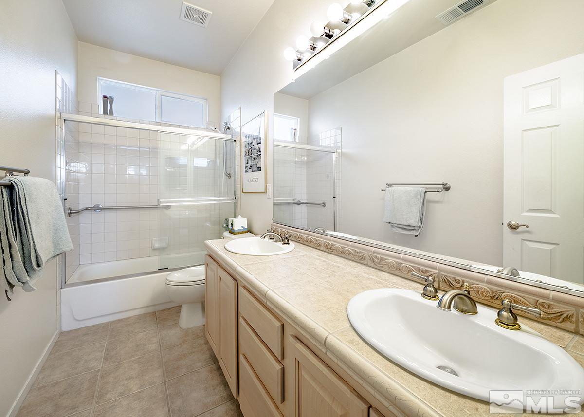 1408 Wild Wolf Way Reno, NV 89521 - Photo 11 of 24 a bathroom with a granite countertop sink a toilet a mirror and shower