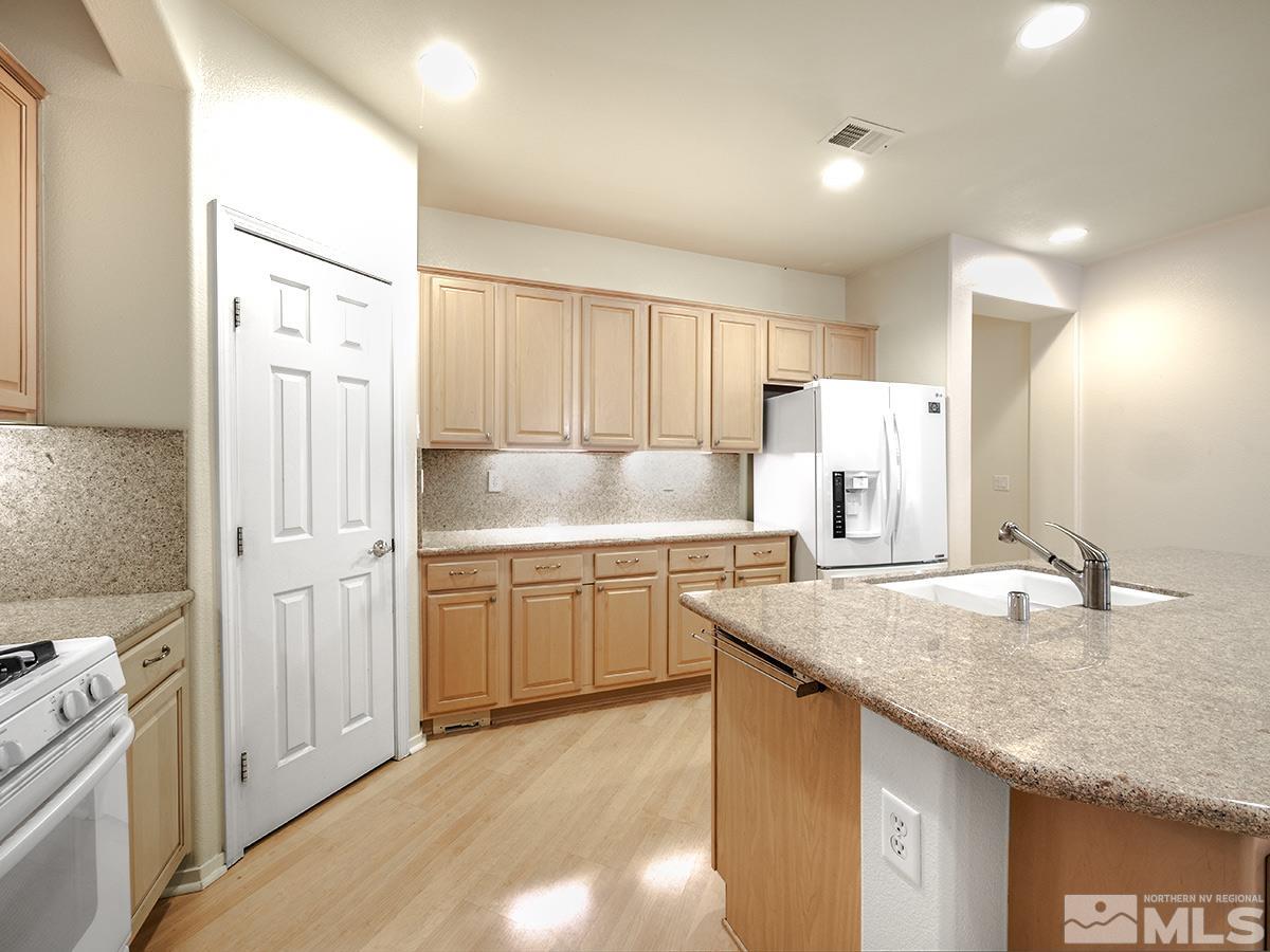1408 Wild Wolf Way Reno, NV 89521 - Photo 7 of 24 a kitchen with stainless steel appliances granite countertop a sink stove and refrigerator