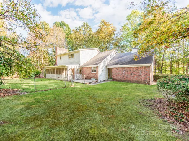 a view of a house next to a big yard and large trees
