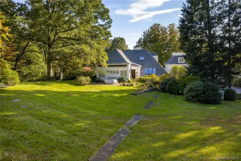 an aerial view of residential house with outdoor space and trees all around