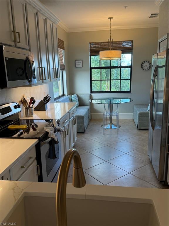9719 Acqua Court, Unit 238 Naples, FL 34113 - Photo 14 of 25 a kitchen with a sink a stove and chairs
