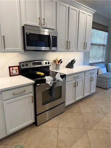 a kitchen with stainless steel appliances granite countertop a stove a microwave and a white cabinets