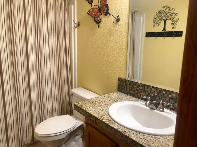 a bathroom with a granite countertop sink toilet and mirror