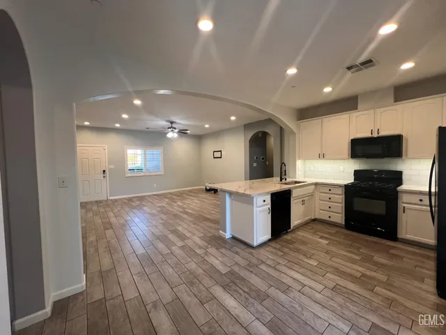 a large kitchen with kitchen island a sink wooden floor and stainless steel appliances