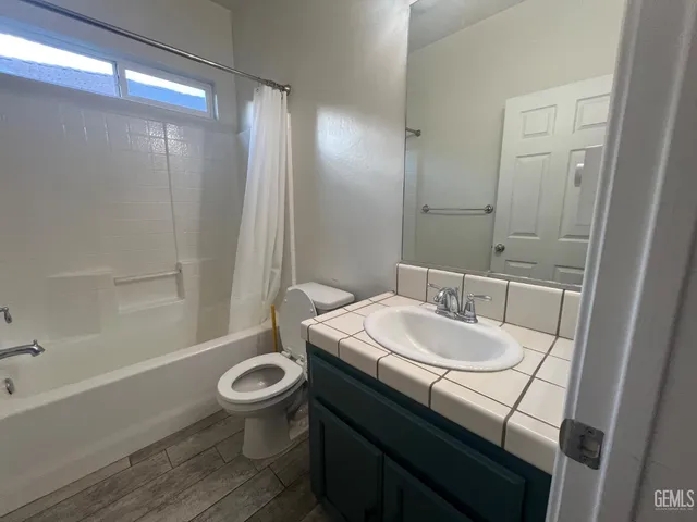a bathroom with a sink a toilet a mirror and shower