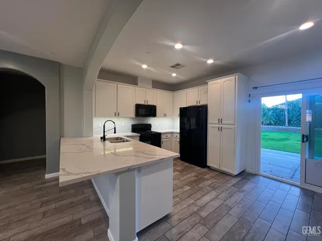 a large kitchen with kitchen island a sink dishwasher a refrigerator and a stove with wooden floor